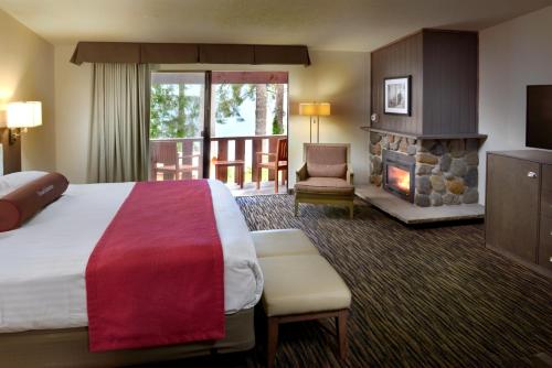 Lake Quinault Lodge في كويناولت: غرفة فندقية بها سرير وموقد