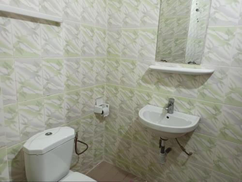 ein Badezimmer mit einem WC, einem Waschbecken und einem Spiegel in der Unterkunft Hotel Saint-Jean in Cotonou