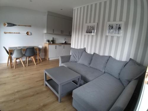 a living room with a gray couch and a table at Przystań na Zagórzu - Apartamenty nad jeziorem in Drezdenko