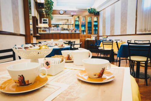 un tavolo con tazze e piattini sopra di esso in un ristorante di Hotel Corallo a La Spezia