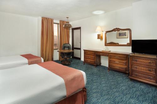 a hotel room with a bed and a desk and a television at Hotel San Jorge in Saltillo