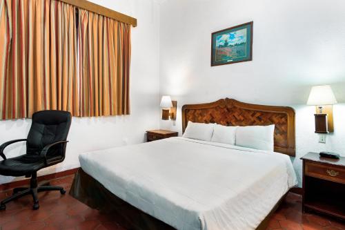 a hotel room with a bed and a chair at Hotel Urdiñola Saltillo in Saltillo