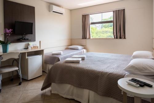 a room with two beds and a desk and a window at Holambra Garden Hotel in Holambra