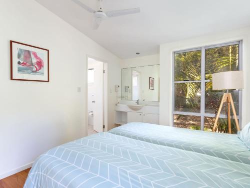 a white bedroom with a bed and a window at Mobys Beach house 11 in Boomerang Beach