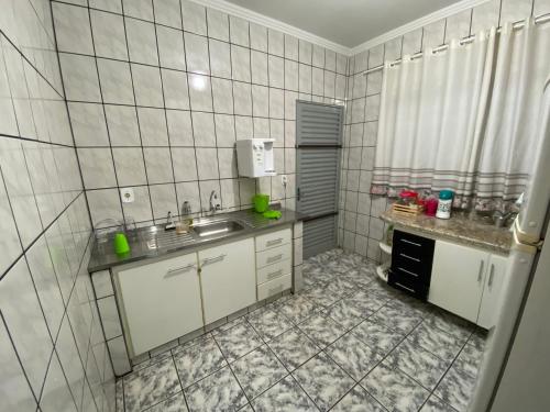 cocina de azulejos blancos con fregadero y ventana en Casa em Caldas Novas, en Caldas Novas