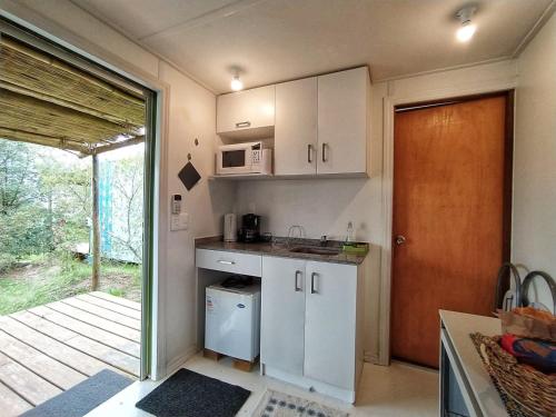uma cozinha com armários brancos e uma porta para um pátio em La Práctica em Carmelo