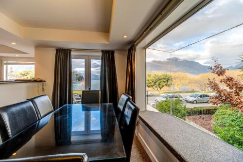 a dining room with a table and chairs and a large window at Lakefront Apartments,18 LAKE ESPLANADE ROAD in Queenstown