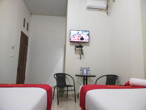 a room with two beds and a tv on the wall at Gosyen Efata Toraja Hotel in Makale