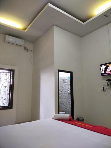 a bedroom with a bed and a tv on the wall at Gosyen Efata Toraja Hotel in Makale