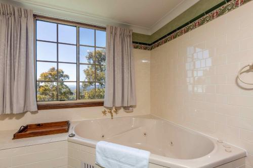 W łazience z oknem znajduje się biała wanna. w obiekcie Bimbadeen Mountain Retreat w mieście Mount View