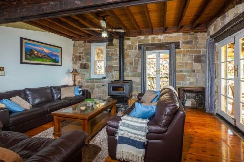 a living room with leather furniture and a stone wall at Bimbadeen Mountain Retreat in Mount View
