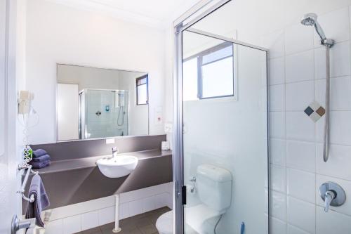 a bathroom with a toilet, sink, and shower stall at Ascot Lodge Motor Inn in Kingaroy