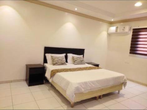 a bedroom with a bed in a white room at Rose Tulip Served Apartments وردة الخزامى للشقق المخدومة in Riyadh