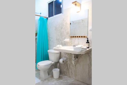 a bathroom with a toilet and a sink and a mirror at Casa Universo Holbox in Holbox Island