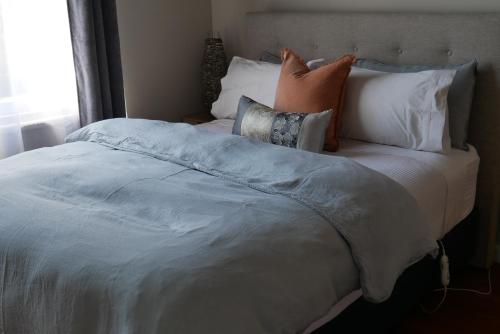 a bedroom with a large bed with pillows at Havelock Cottage on St Georges in Havelock North