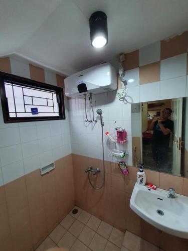 a bathroom with a shower and a sink and a mirror at VILLA PANDA G Kota Bunga Puncak in Cinengangirang
