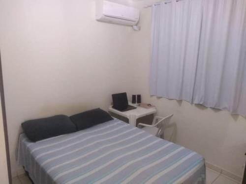 - une chambre avec un lit et un bureau avec un ordinateur portable dans l'établissement Apt completo-Ar-TV-Portaria 24h-Piscina-Praia, à Campos dos Goytacazes