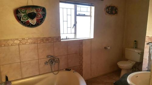 Un baño con bañera, inodoro y ventana. en House, Cottage and Contractors Manor, en Meyerton