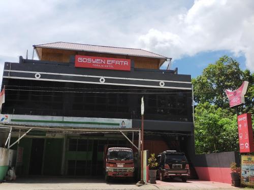 a building with two trucks parked in front of it at Gosyen Efata Toraja Hotel in Makale