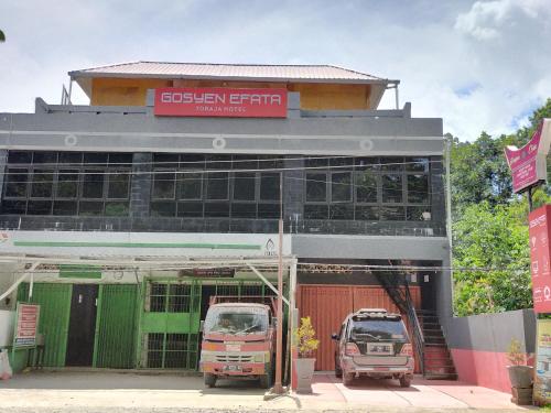 two trucks parked in front of a building at Gosyen Efata Toraja Hotel in Makale