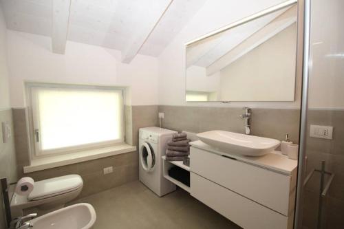 a bathroom with a sink and a washing machine at La mansarda di Rossella in Pieve Di Ledro