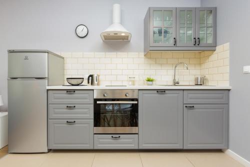 - une cuisine avec des placards gris et un réfrigérateur blanc dans l'établissement Apartments Warsaw Bitwy Warszawskiej, à Varsovie