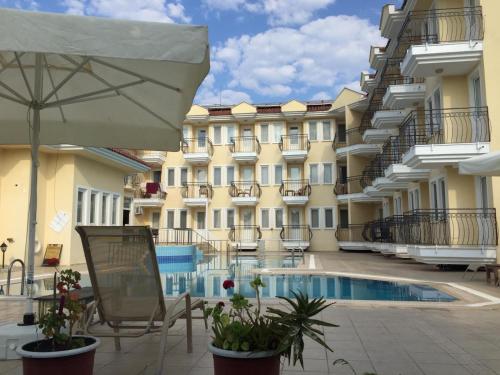 um pátio do hotel com uma piscina e um guarda-sol em VERDE PORT HOTEL em Fethiye