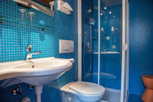 a blue tiled bathroom with a sink and a shower at BB Garni Motta in Airolo
