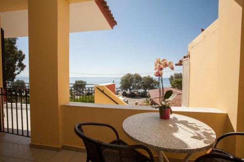 a table and chairs on a balcony with a view of the ocean at Panagiota Apartments in Mavrovoúnion
