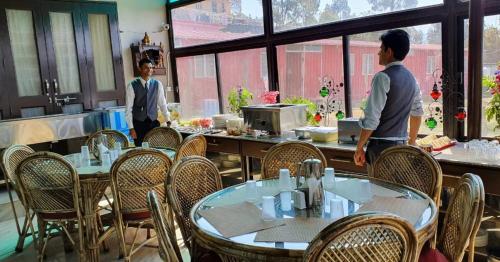 two people standing in a restaurant with tables and chairs at Samskara & Samsara in Lansdowne