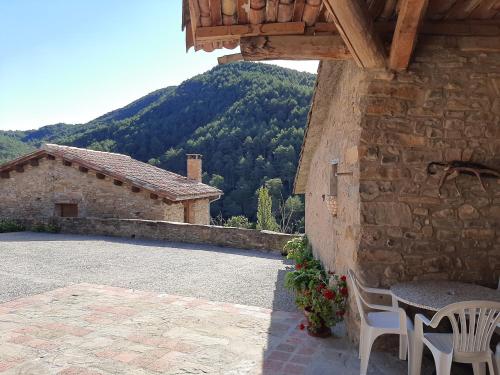 a patio with a table and chairs and a mountain at Casa Rural Mas Pujol in Campdevánol