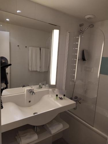 a bathroom with a sink and a shower and a mirror at Holiday Inn Lille Ouest Englos by IHG in Englos
