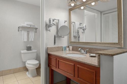 a bathroom with a sink and a toilet and a mirror at Carlsbad by the Sea Hotel in Carlsbad