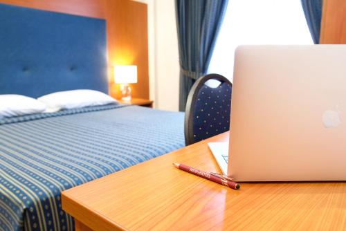 einen Laptop auf einem hölzernen Schreibtisch mit einem Bett in der Unterkunft Hotel Mec in Mailand