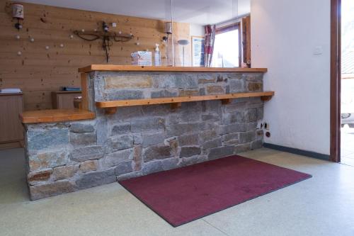 a stone fireplace in a room with a red rug at Résidence Odalys L'Ouillon in Saint-Sorlin-dʼArves