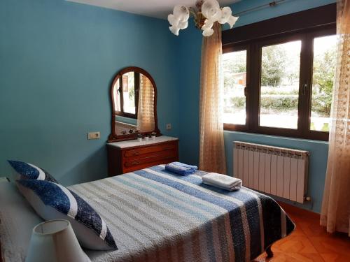 a blue bedroom with a bed and a mirror at Casa Entremolin in Belmonte de Miranda