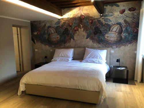 a bedroom with a large bed with a painting on the wall at Villa Cantoni Marca in Sabbioneta