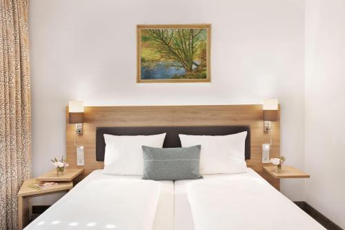 a bedroom with a white bed and a painting on the wall at Landhotel Beck in Kupferzell