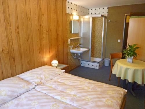 a bedroom with a bed and a sink and a table at Pension Schönblick in Saas-Grund