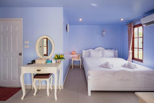 - une chambre bleue avec un lit blanc et un miroir dans l'établissement Sakarin Valley Resort, à Kanchanaburi