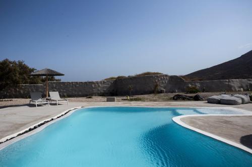 une grande piscine bleue avec 2 chaises et un parasol dans l'établissement Villa Beltramo Santorini 2 bedroom private pool villa, à Foinikiá