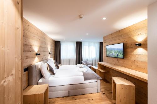 Habitación de hotel con cama y TV en Posthotel Valbella en Valbella