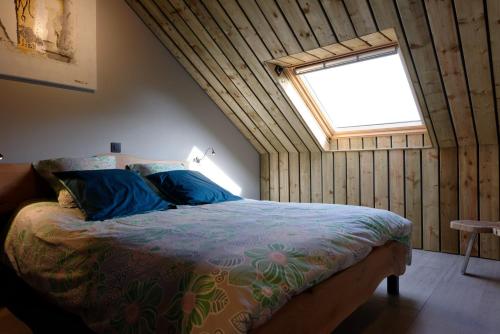 Un dormitorio con una cama con almohadas azules y una ventana en la Nouchettière en La Roche-en-Ardenne