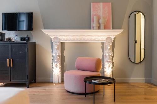 a living room with a pink chair and a mirror at Hôtel Vedette in Profondeville