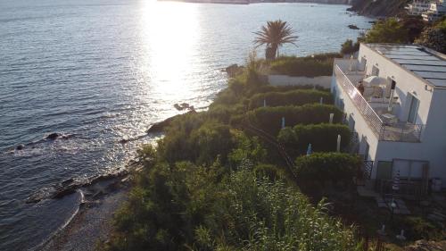 a house on a hill next to the water at La Rosa dei Venti Resort in Piombino