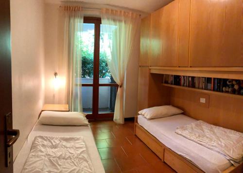 2 Betten in einem kleinen Zimmer mit Fenster in der Unterkunft Ferienwohnung Pepiniere in Ospedaletti