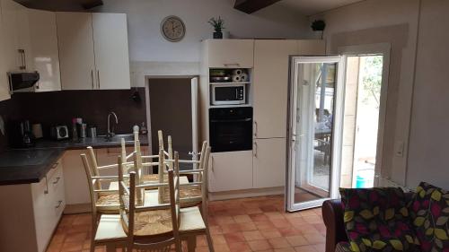 une cuisine avec des armoires blanches et une table et des chaises dans l'établissement Mazet du ruisseau, aux Baux-de-Provence