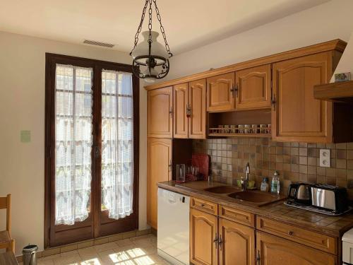 una cucina con armadi in legno e frigorifero bianco di Maison Vigneronne a Loupian