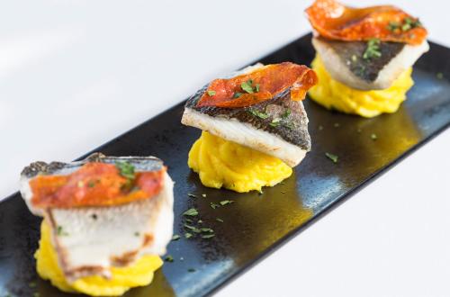 a black plate with three different types of food at Hotel Sporting in Rimini