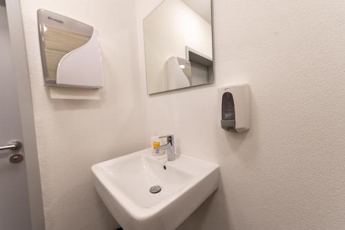 a bathroom with a sink and a mirror at Stadthaus Seeblick G5 - Hostel in Friedrichshafen